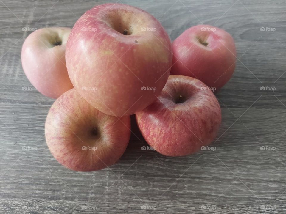 A few red apples placed on a wooden table
