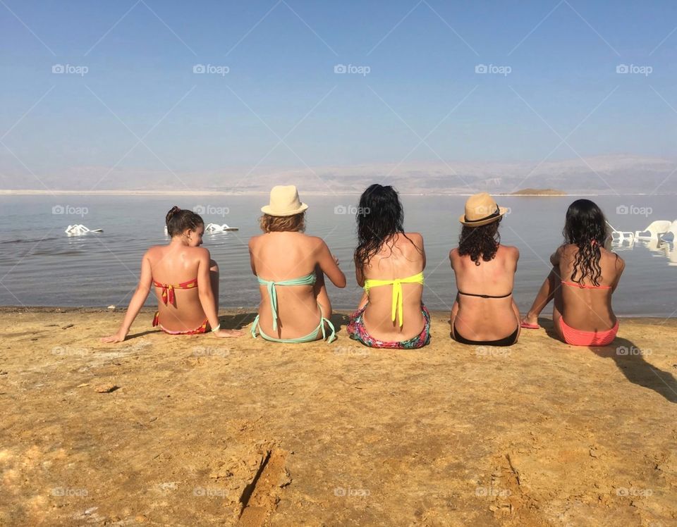 Backless girls sitting on the shore