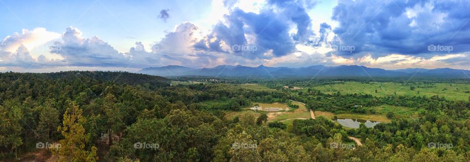 Panoramic view of beautiful scenery of countryside farming area of Chiang Mai, Northern Thailand. Green tropical forest, farmland, mountains, big blue sky and clouds.  