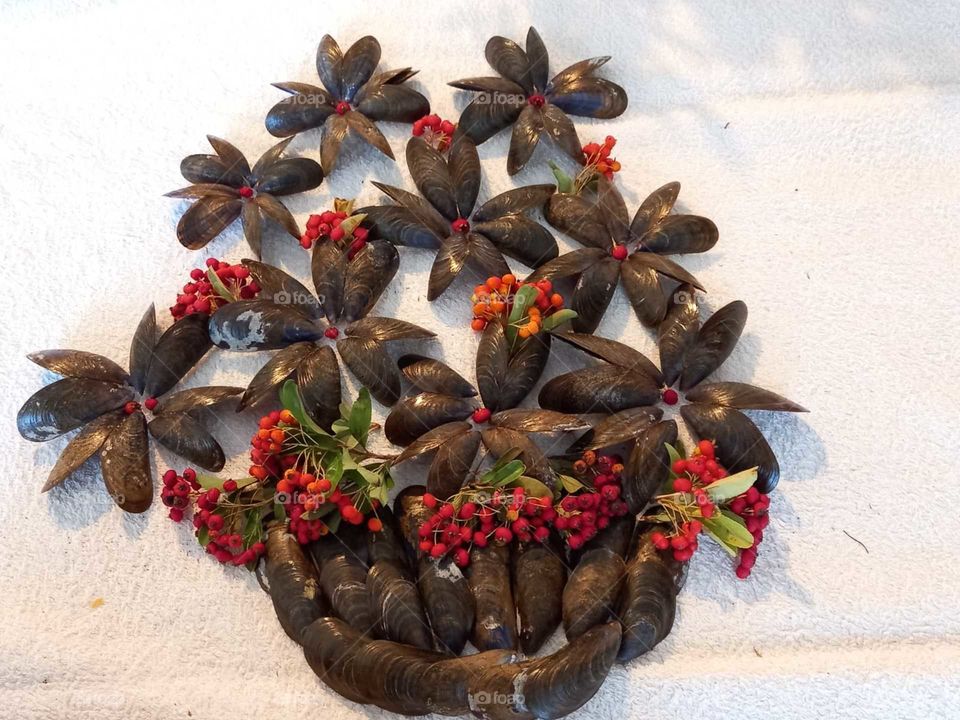 A pot with flowers of shells and berries