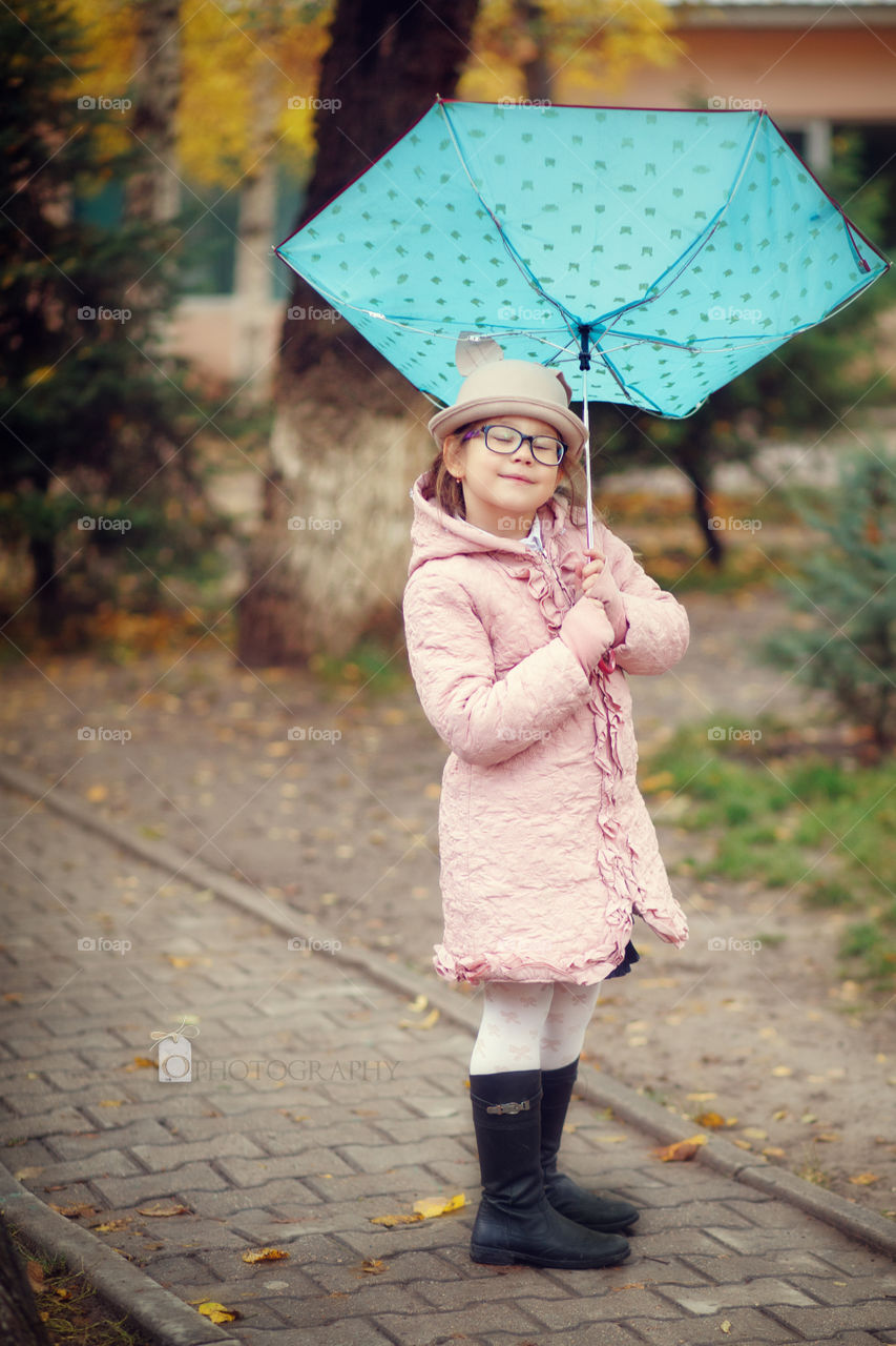 Small girl holding umbrella in hand