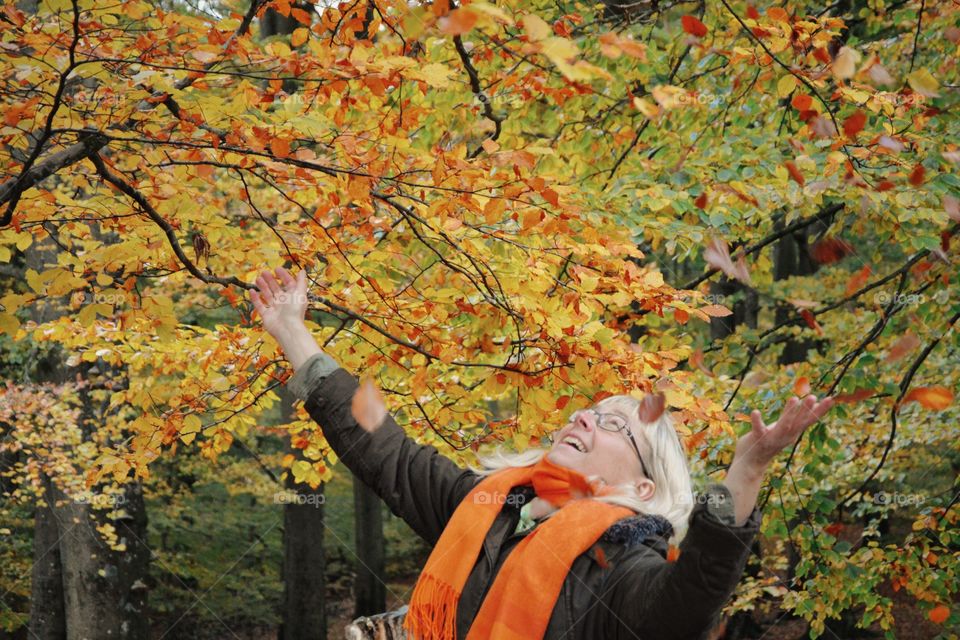 Happy woman under trees during autumn 
