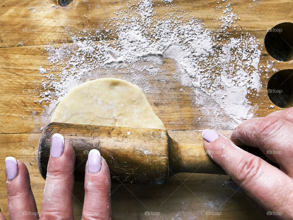 Female hands preparing homemade food from dough on rustic wooden table 