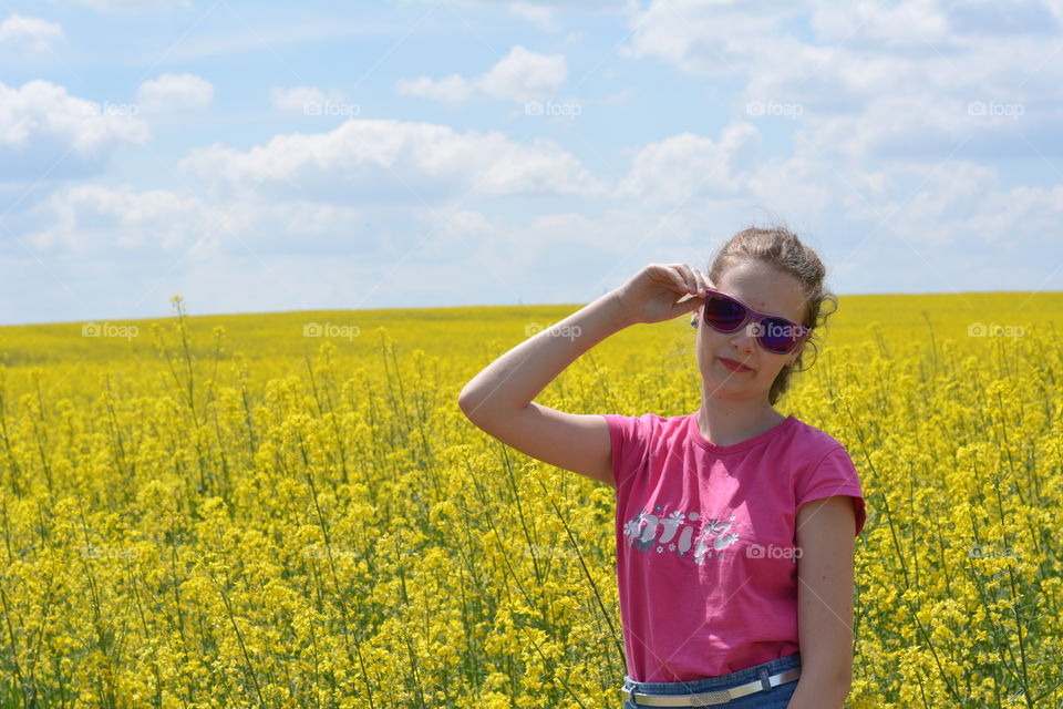 beautiful girl on a yellow flowers rapeseed field background