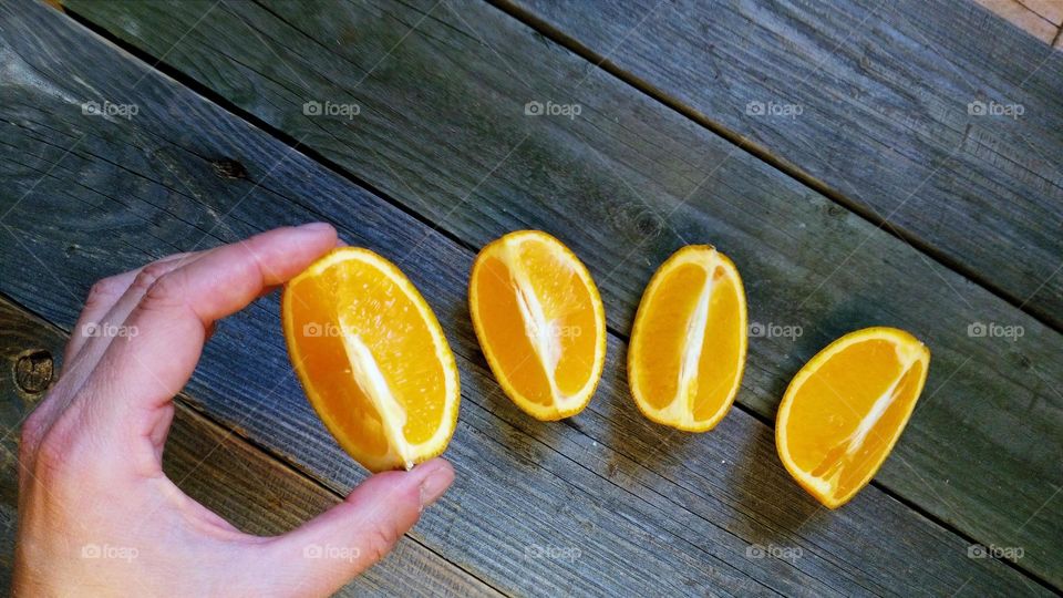 A man's hand holds an orange slice