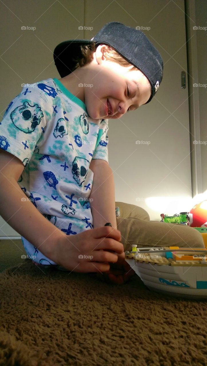 young happy boy playing with lego and being creative in his room