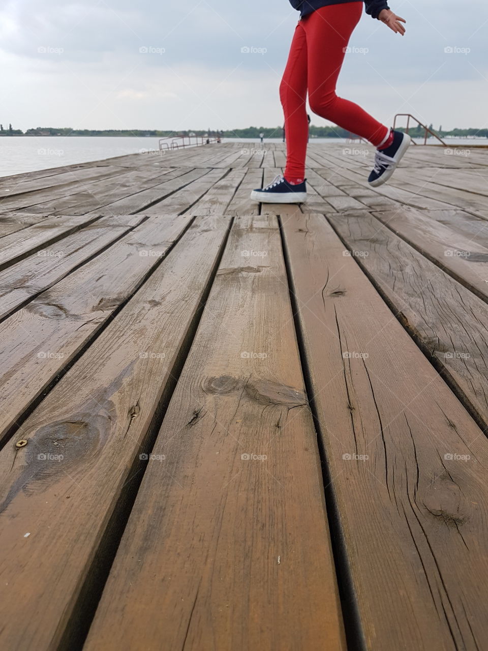 girl with red trousers on the lake dock