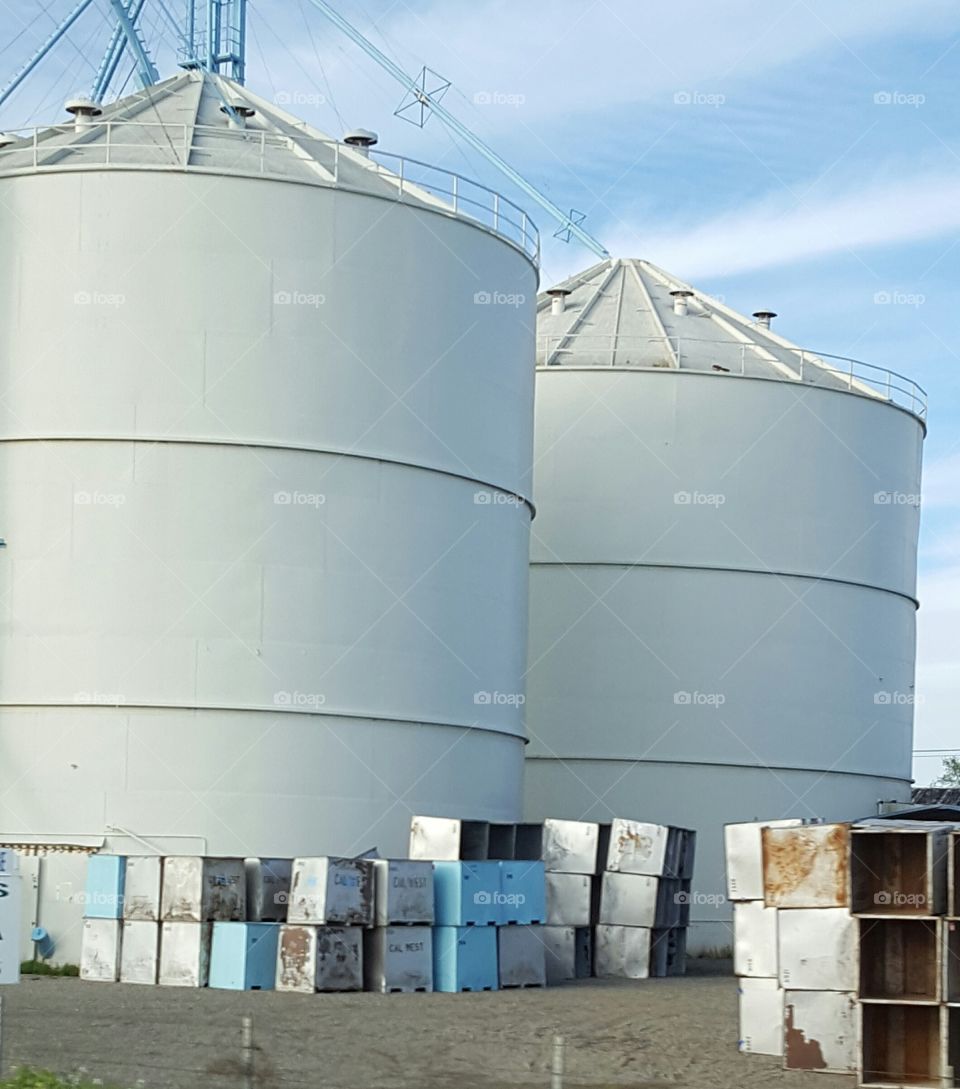 huge fat silos along the highway surrounded by rusting metal.