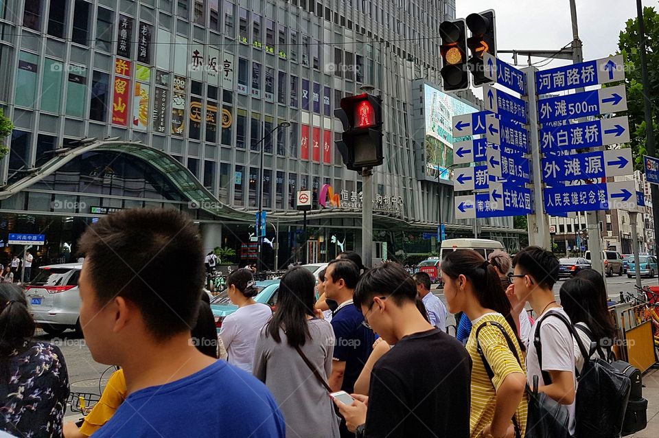 Pedestrians waiting to cross the street in central Shanghai, China.