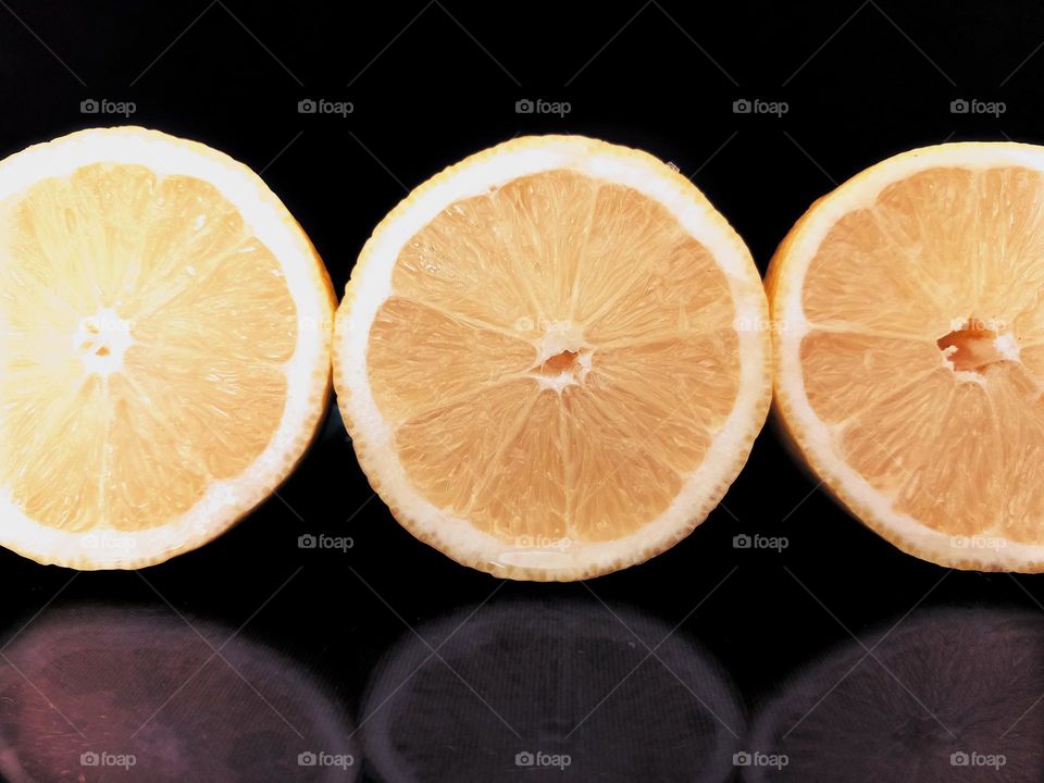 yellow lemon slices on black glass background.