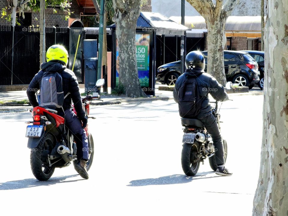 Motorcyclists on two very different types of motorcycles. One is powerful and big, while the other is cheaper and less expensive. Both are equally versatile in a big city.
