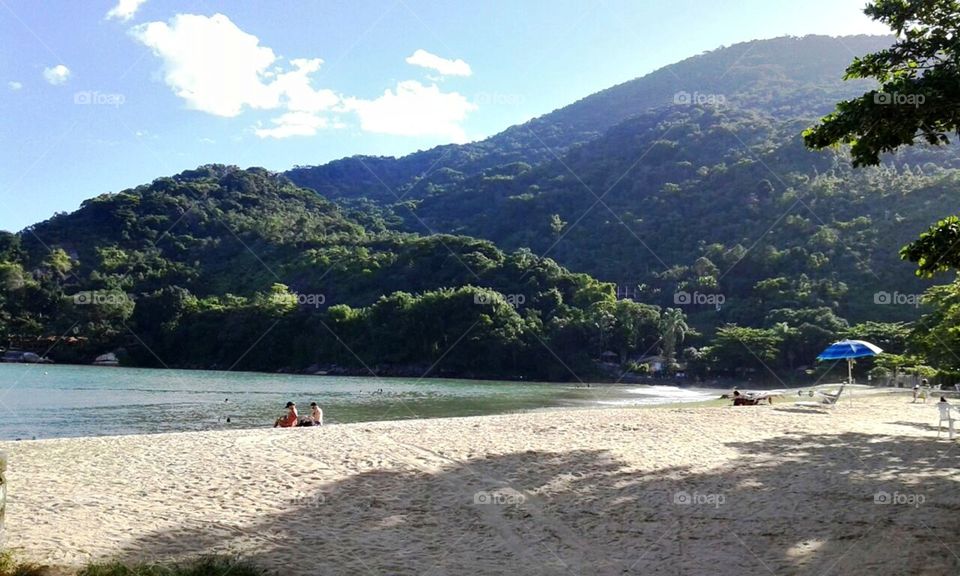 Beleza das águas, árvores, céu, montanhas e nuvens, em praia brasileira.