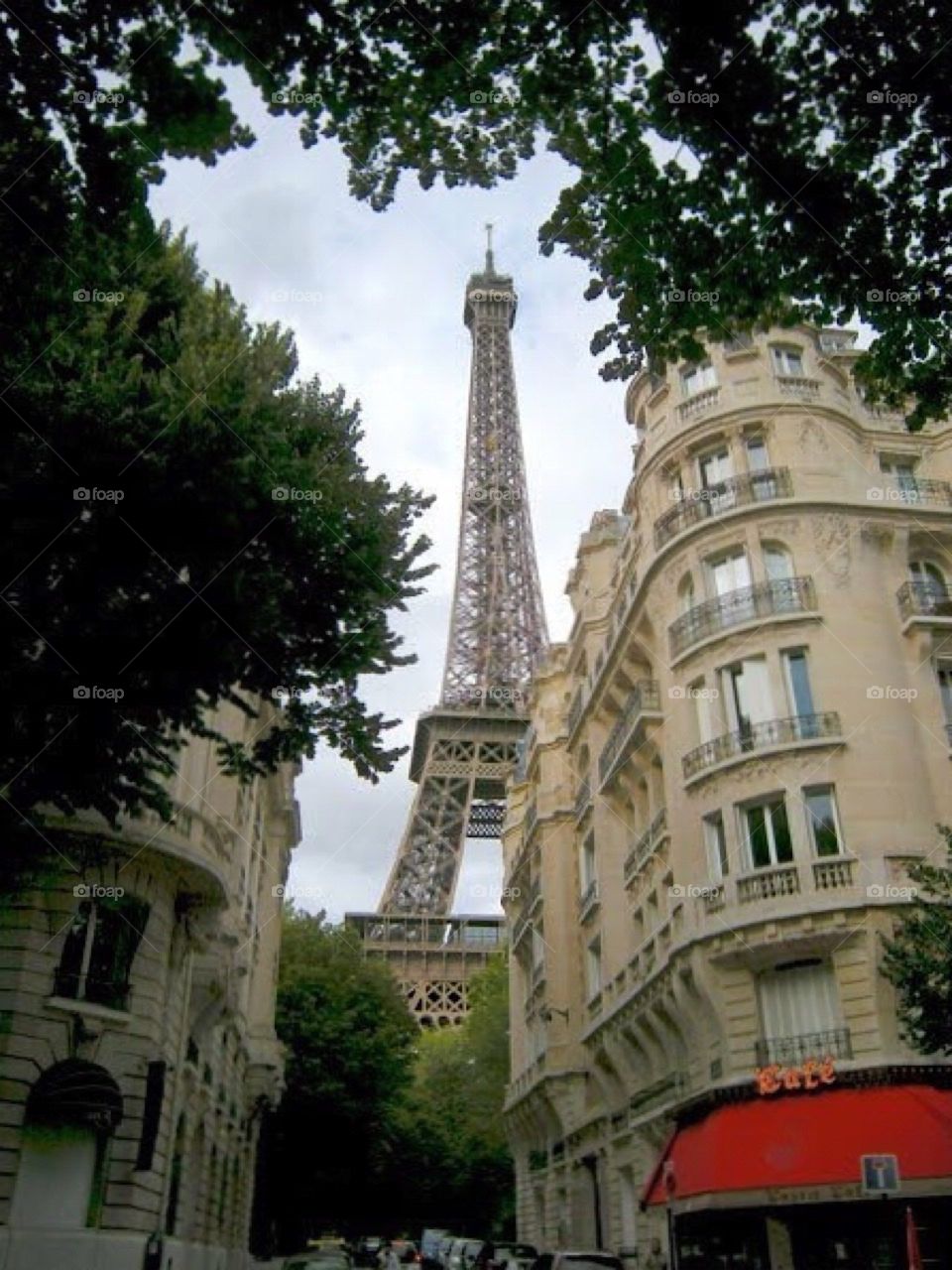 Eiffel Tower behind buildings and trees. Paris France. Europe.
