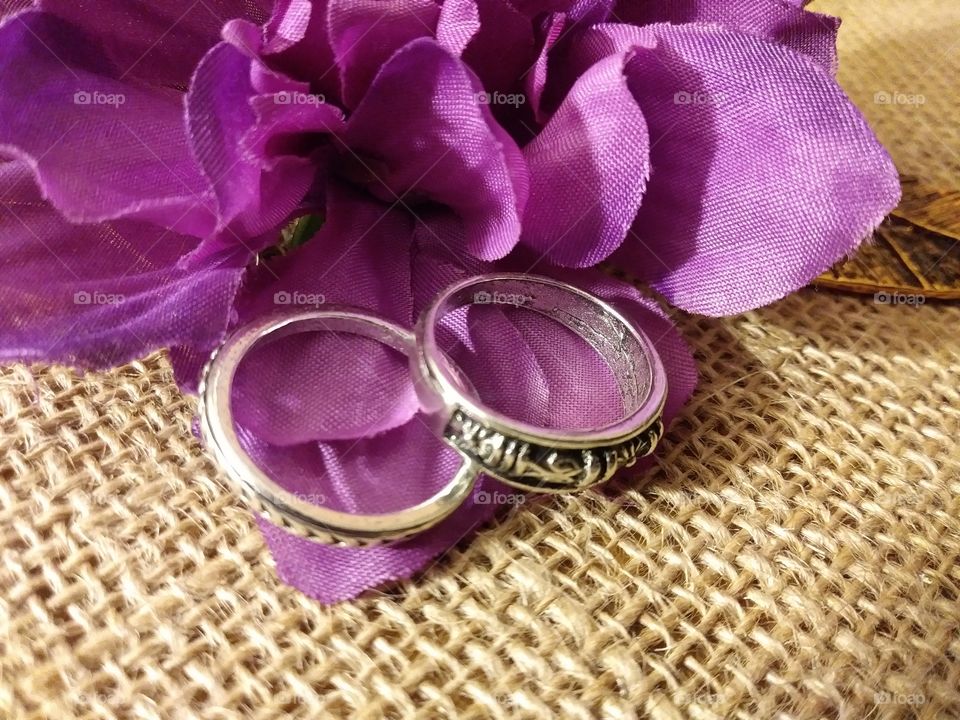 Two rings among a purple silk flower