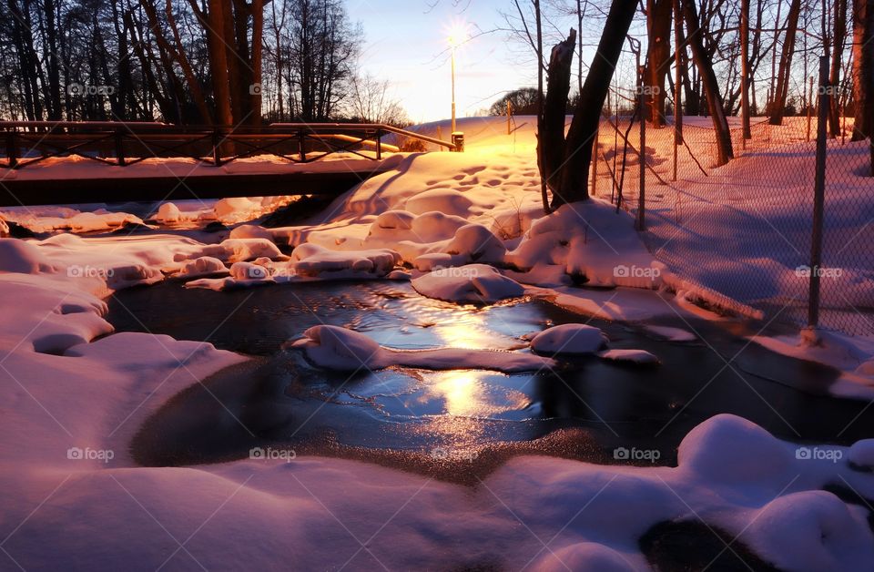 Frozen river in Helsinki. Almost completely frozen scenic small river captured on a very cold evening in Helsinki, Finland, during the coldest part of the winter.