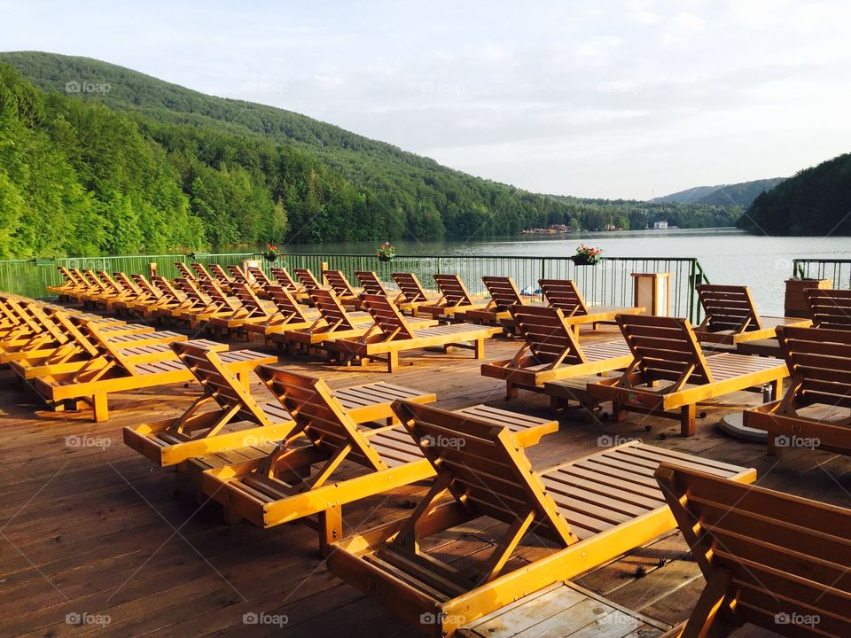 Beach with empty wooden sunbeds near the lake