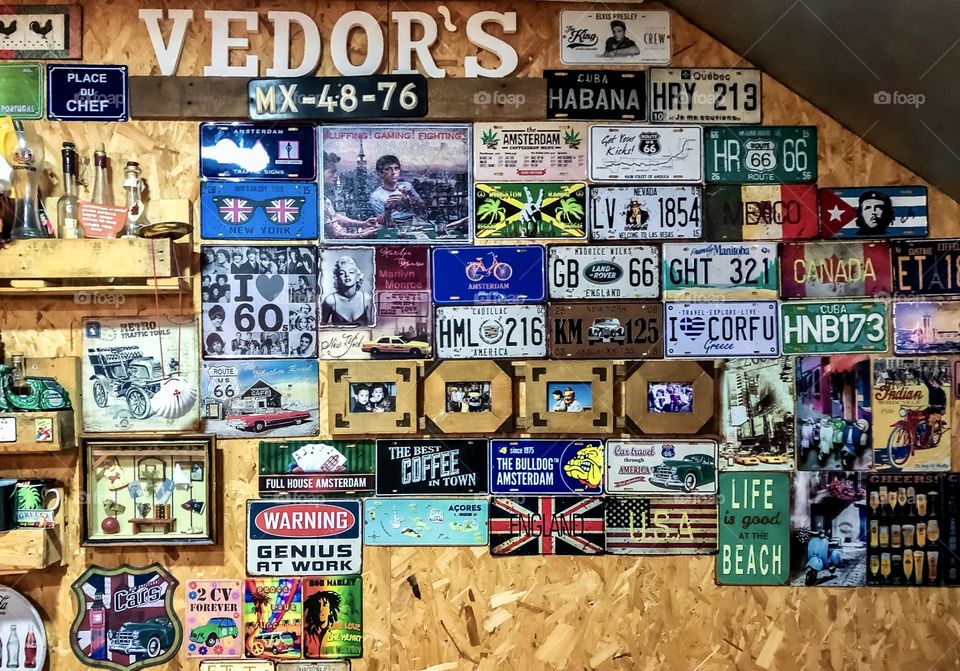 A collection of signs, photo, number plates on the wall of a cafe