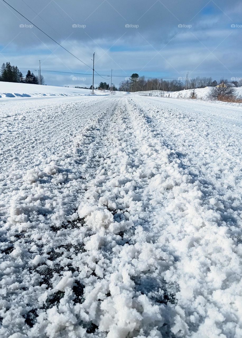 Fresh tire tracks through newly fallen bright white snow on a country road in New England.
