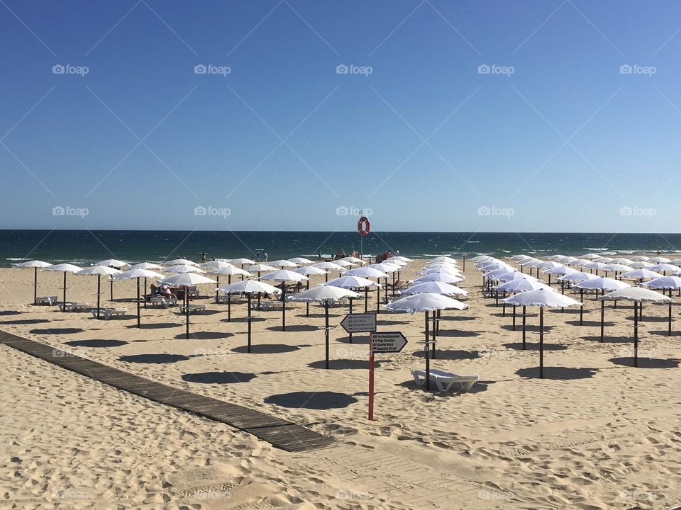 Lines of white parasols on empty beach