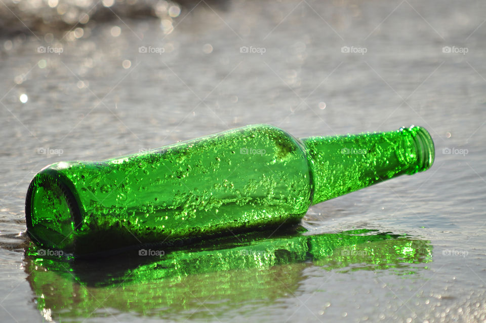 Green bottle on the beach