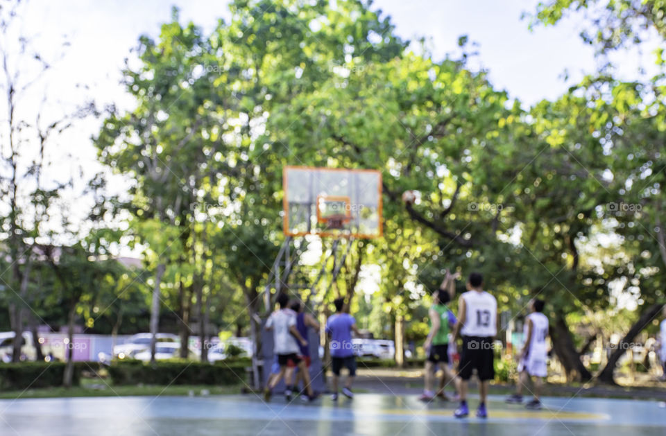 Blurry image of elderly men and teens playing basketball in the morning at BangYai Park , Nonthaburi in Thailand.