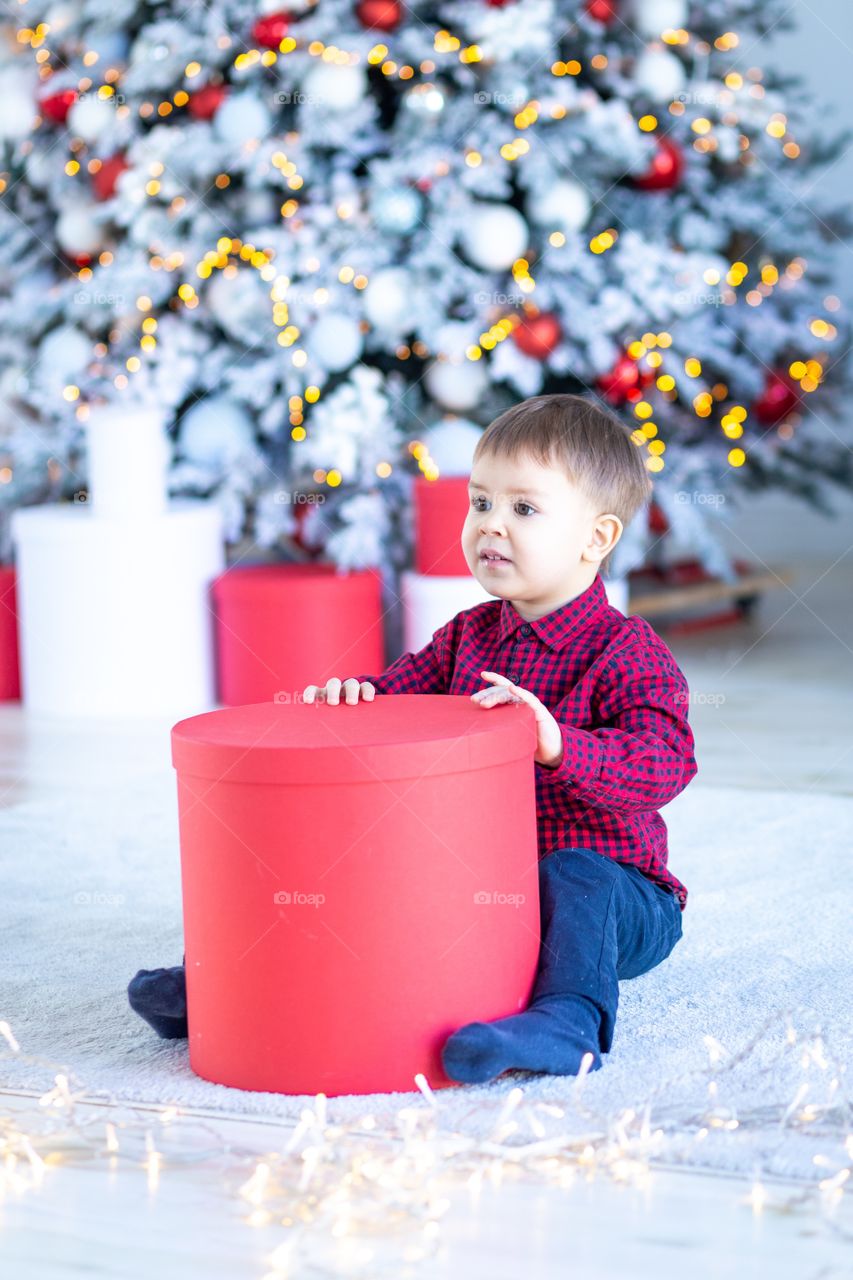 boy and gift box next to christmas tree