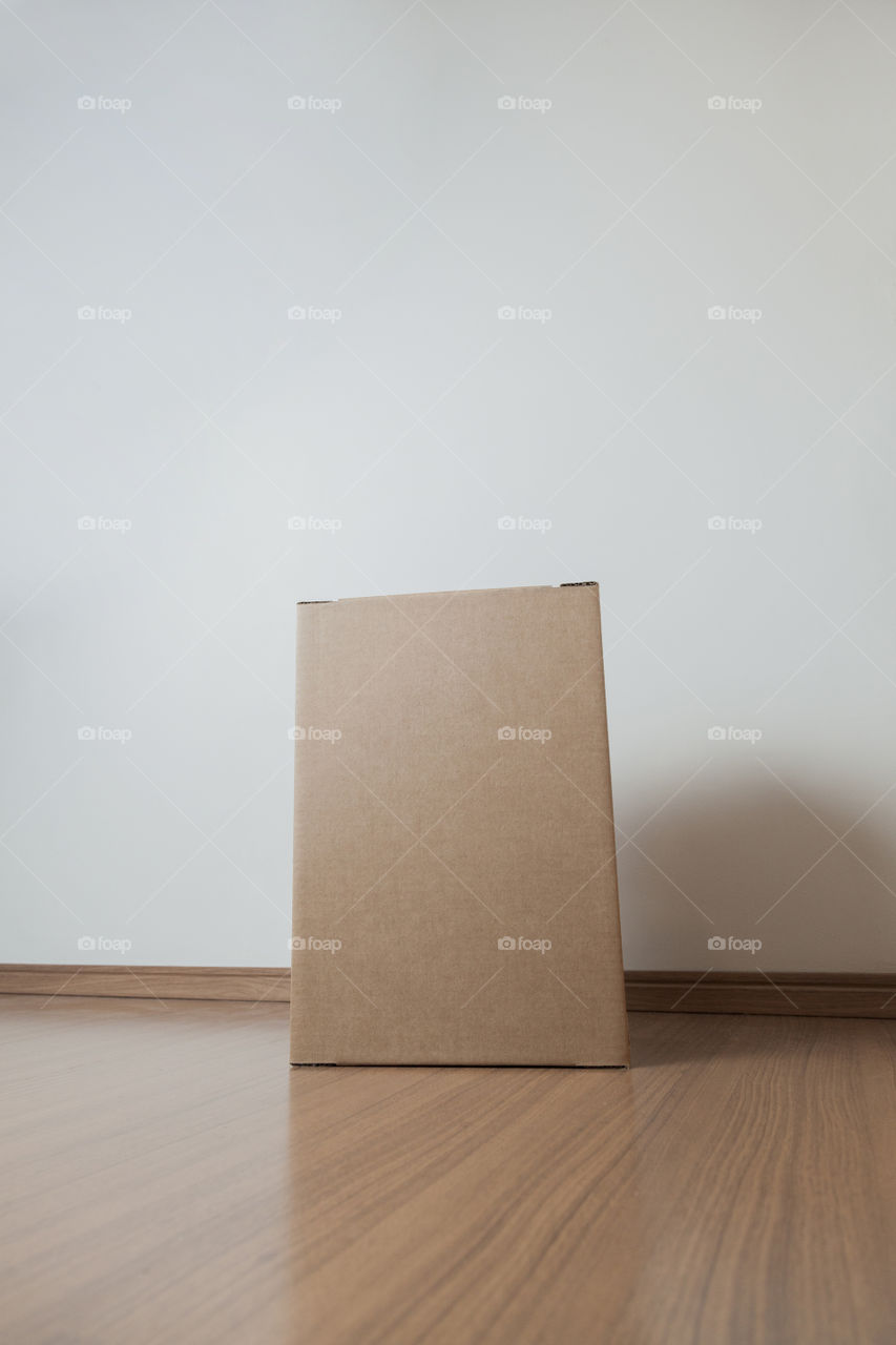 Cardboard box with order placed on the floor in an empty room with a neutral background. delivery concept. economy concept. business concept. shopping concept. copy space. Nobody