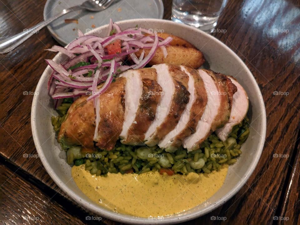 Delicious Peruvian dinner with chicken, vegetables, and fried plantains. The chicken slices spread aesthetically across the plate