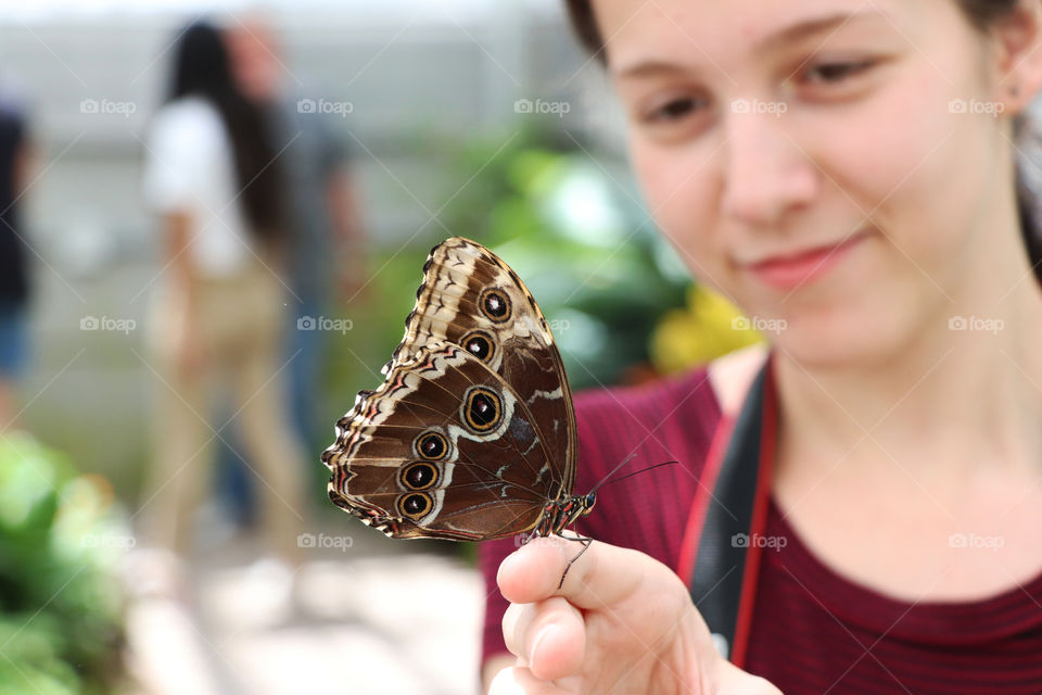 Young woman holding a large brown butterfly on her finger