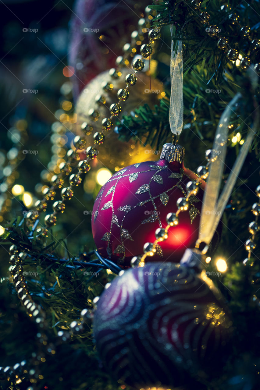 A portrait of a christmas ball hanging in a christmas tree together with other ornaments.