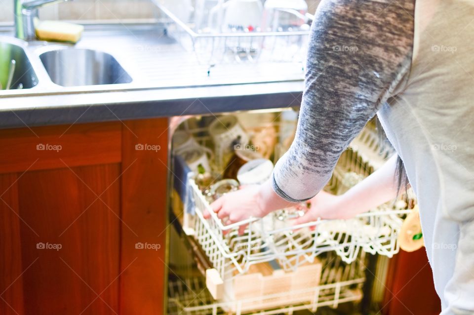 Person removing kitchen utensil from dishwasher