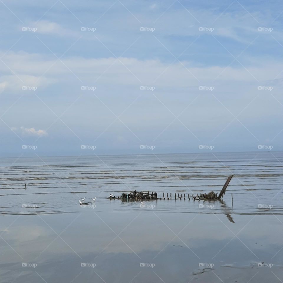 Boat wreckage beach reflection optical illusion