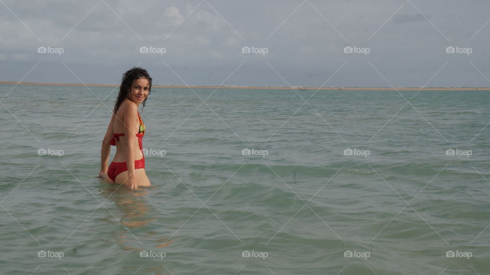 Smiling young woman standing in sea