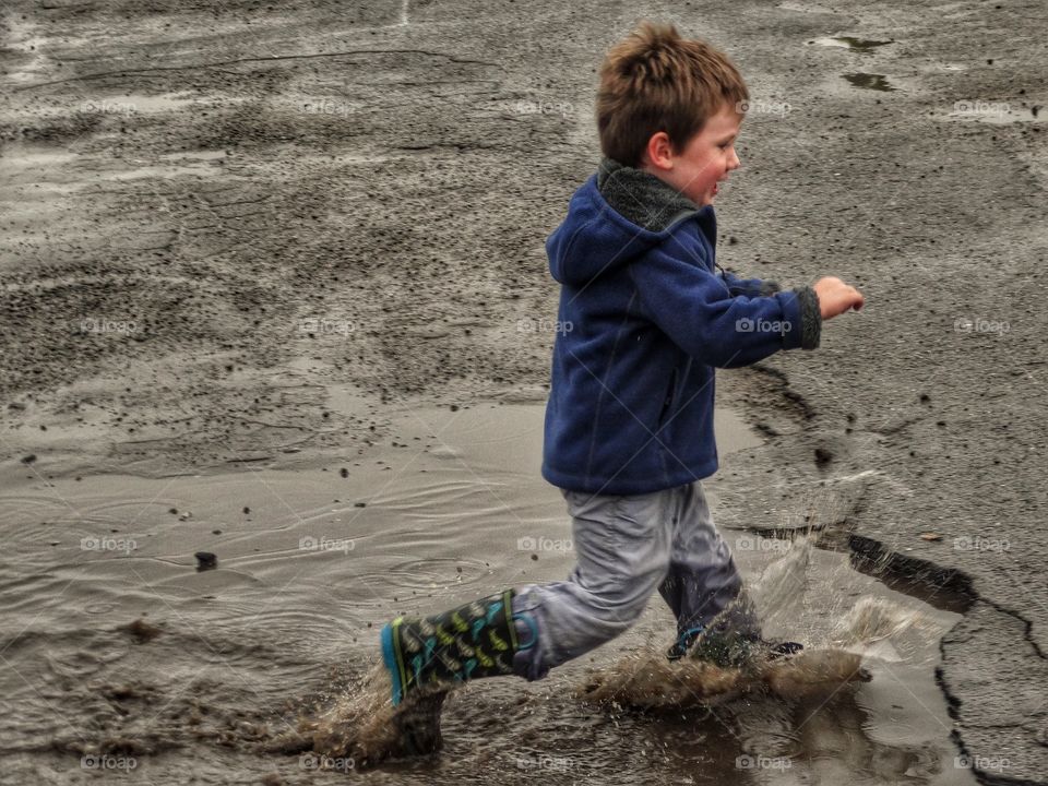 Love Running. Young Boy Running Through A Puddle
