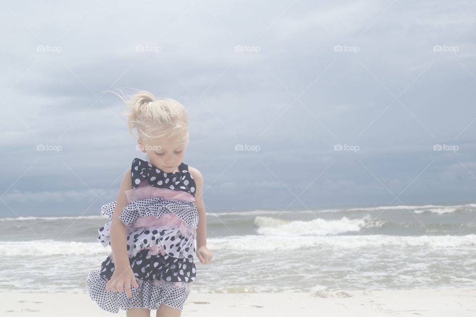 Little girl walking on the beach with a storm approaching 