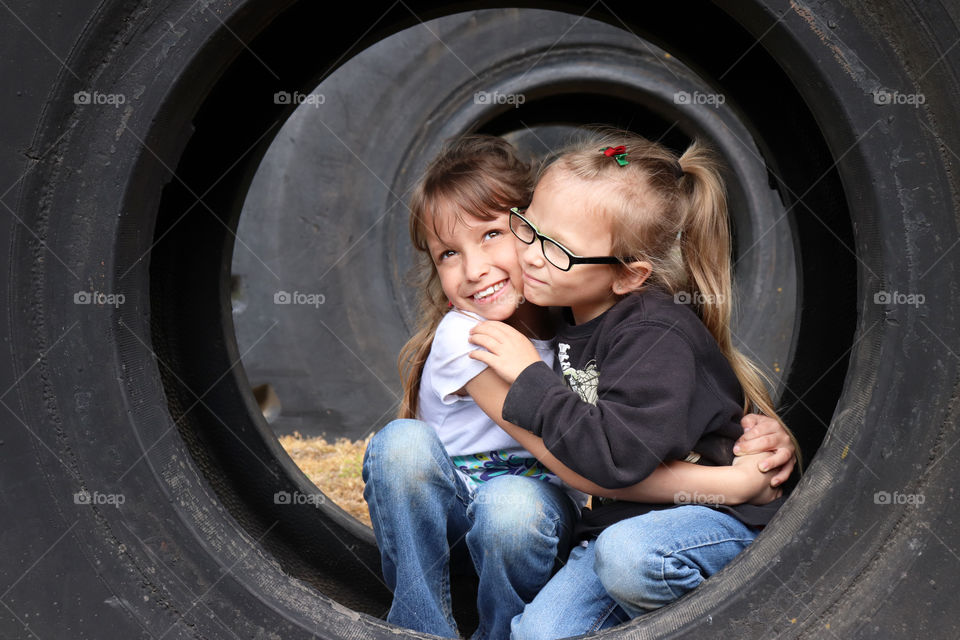 Sisters sitting in a tire, hugging each other
