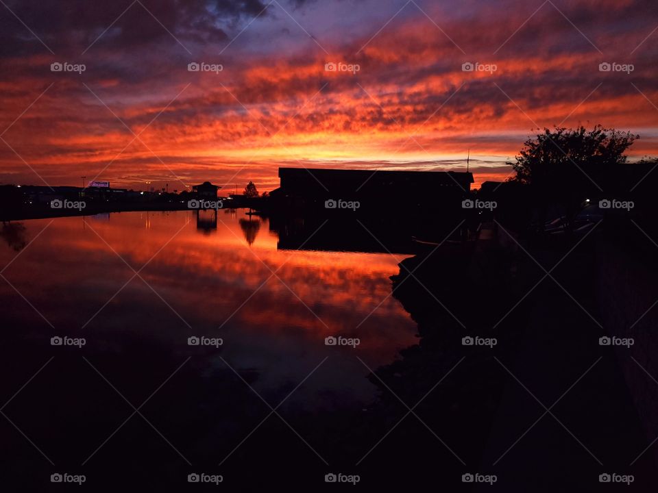 A stunning sunset is reflected in a small pond in Broken Arrow, Oklahoma