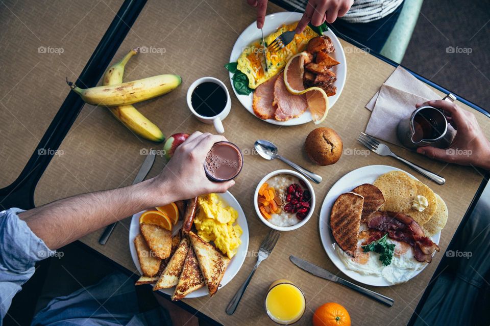 Three people at table with breakfast, view from above.