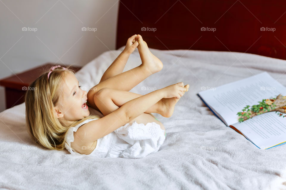 Happy little girl with blonde hair at home 