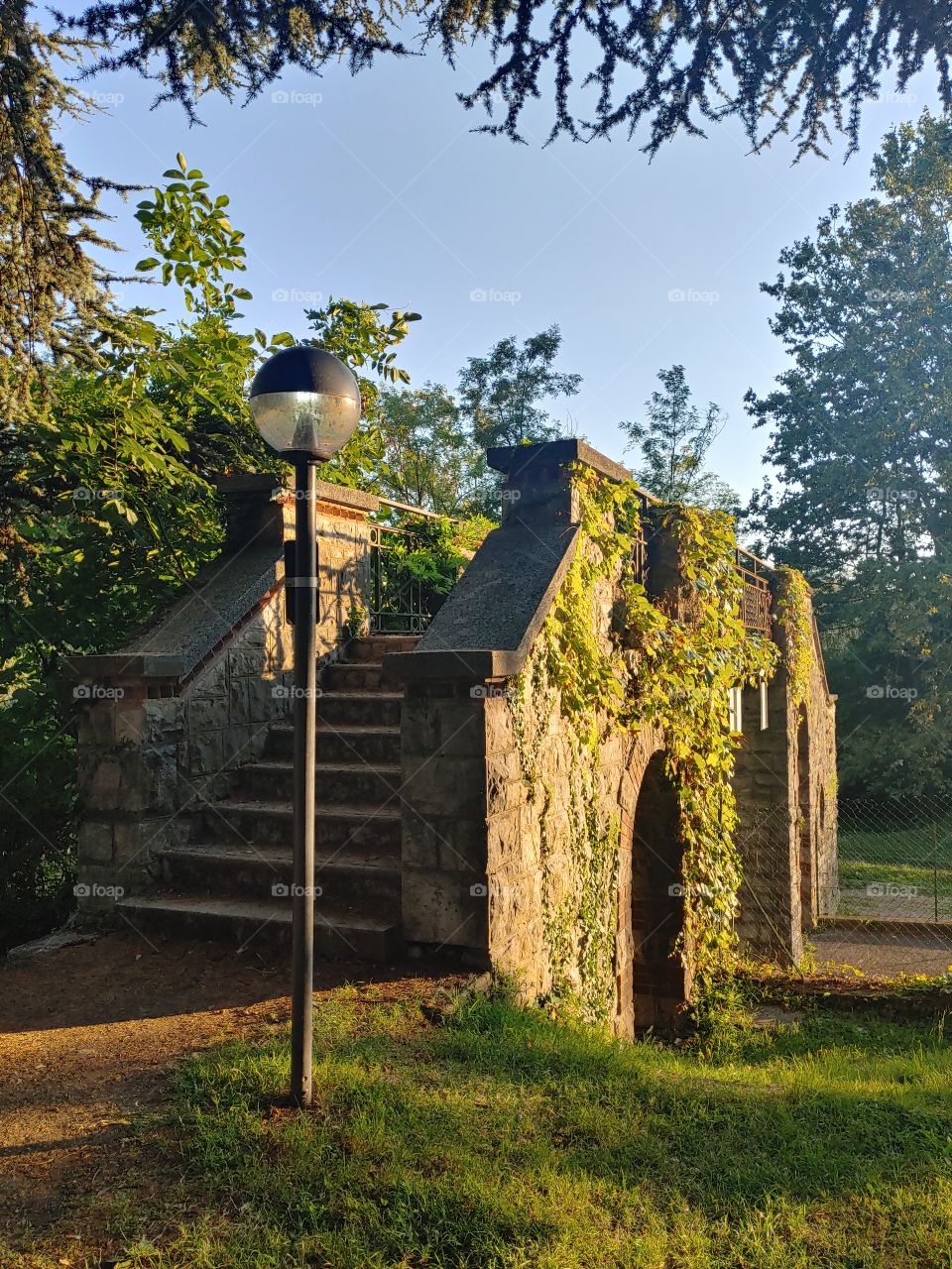 old bridge coveded by ivy, dimmed in late noon sunlight. Park of Villa Toepliz, Varese, italy.