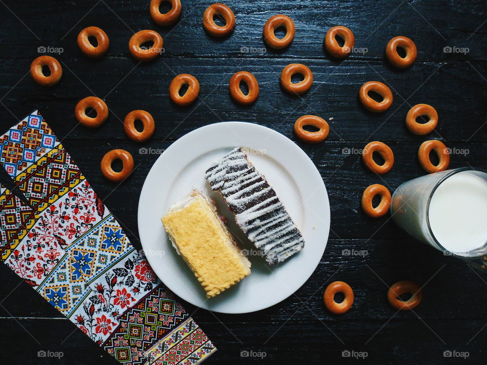 cakes, a cup of milk and bagels on a black background