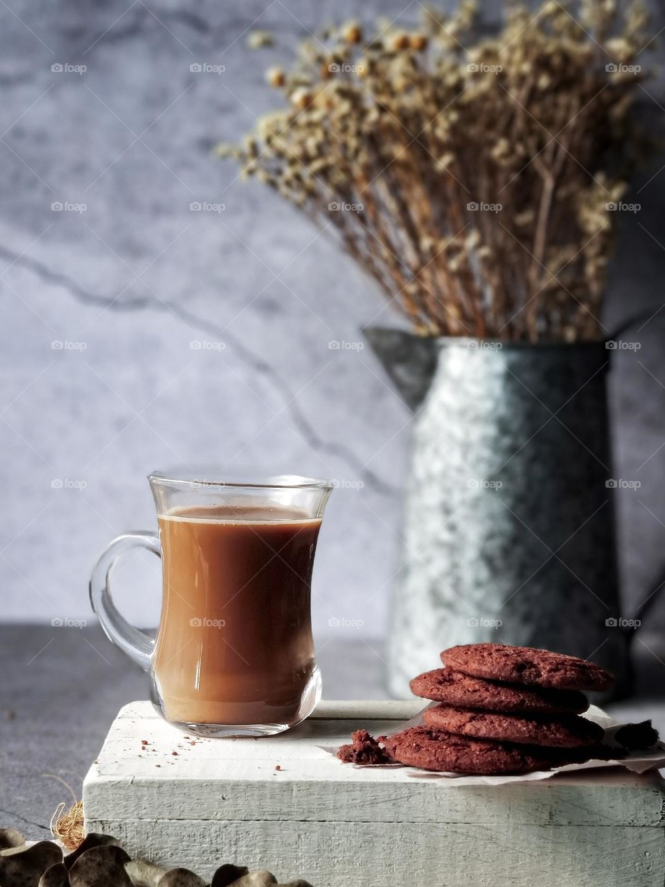 A cup of milk coffee and some biscuits on wooden board in close up view 