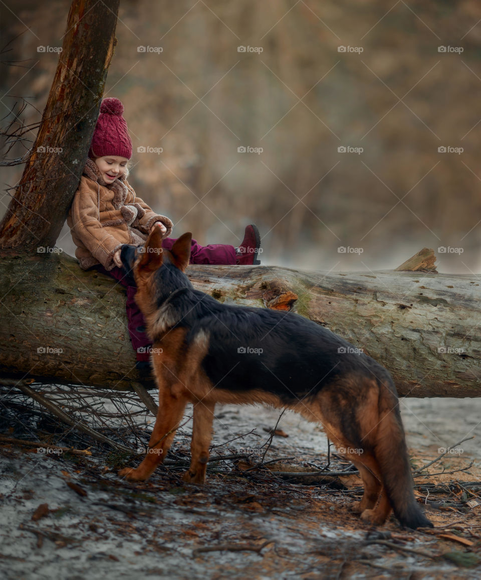 Little girl with German shepherd 6-th months puppy at early spring forest