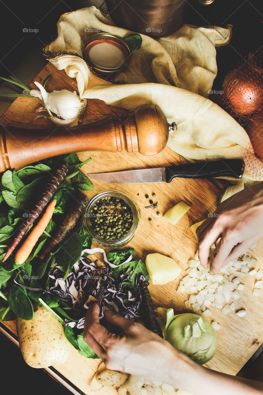 Cooking and preparing fresh vegetables with spinach, cabbage, carrots, kohlrabi, green peppercorn, chopped onion  and sliced potatoes flat lay on wood table 