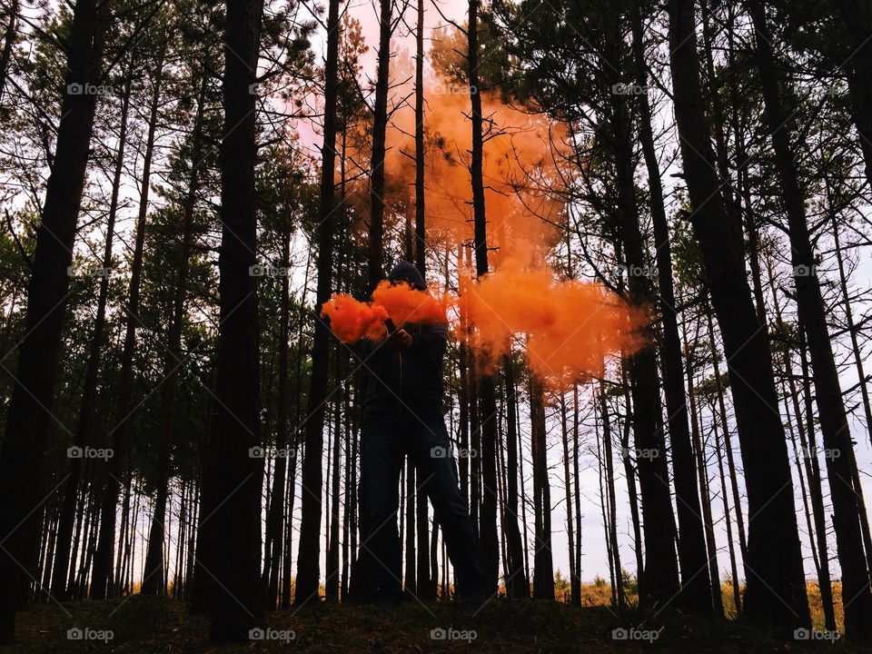 Person standing in forest holding distress flare