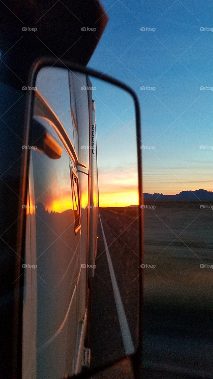 Sunset reflected in the rearview mirror and the side of the truck