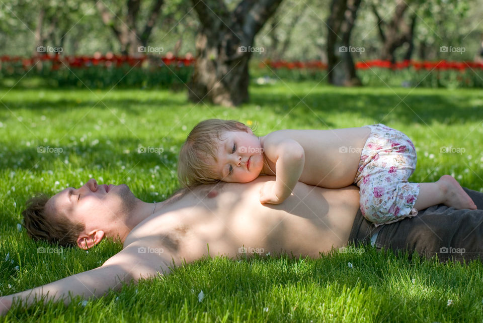 Boy sleeping on his father's chest in the garden