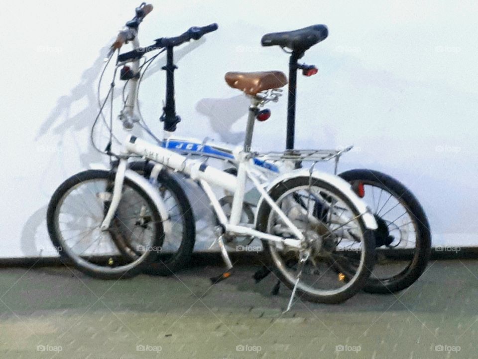 Two bicycles in front of the wall