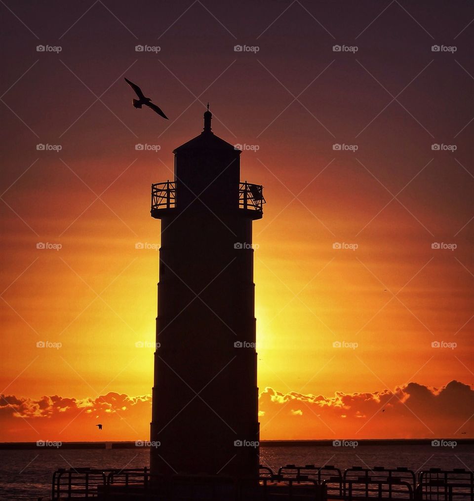 Silhouette of light house at sunset