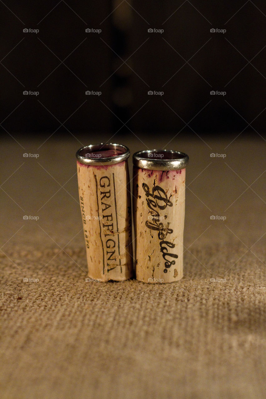 Men's wedding rings perched on top of two red wine corks 